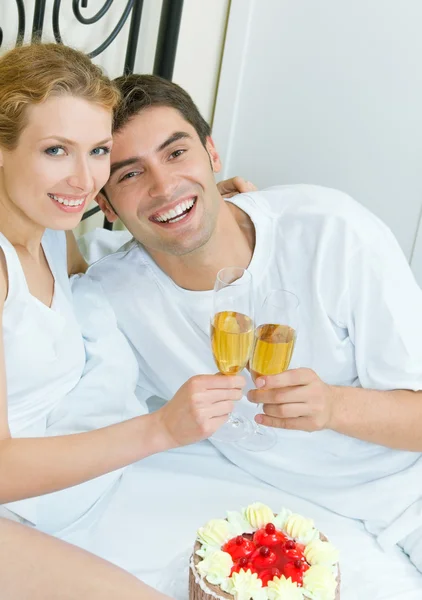 Молодая пара празднует с шампанским в спальне — стоковое фото