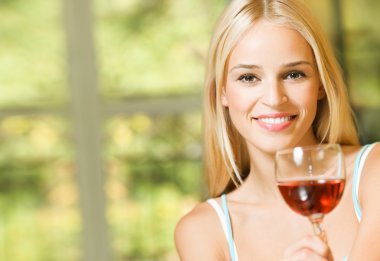 Young smiling woman with glass of red wine, indoors clipart