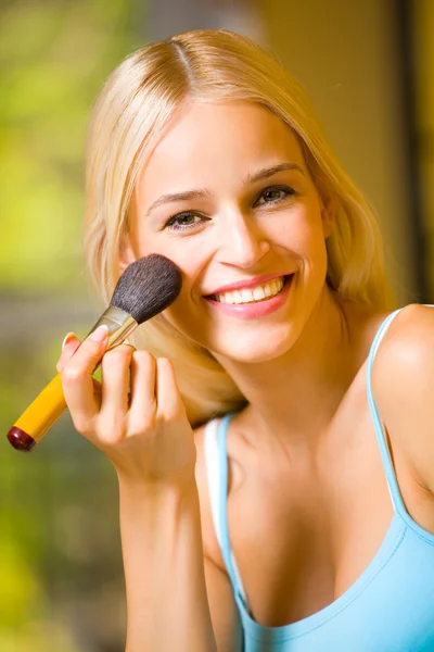 Portret van lachende mooie jonge vrouw met make-up borstel indo — Stockfoto