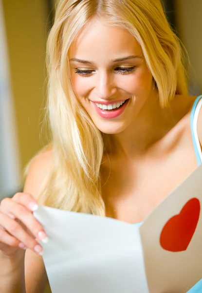 Портрет молодой привлекательной счастливой женщины, читающей валентинку — стоковое фото