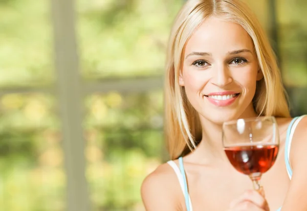 Giovane donna sorridente con bicchiere di vino rosso, in casa — Foto Stock