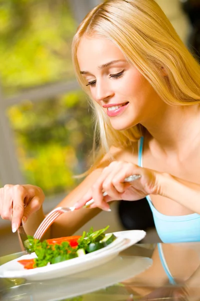 Портрет молодой счастливой улыбающейся женщины, которая ест салат — стоковое фото