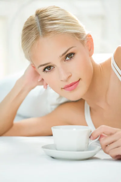 Gelukkige vrouw met kopje koffie of thee bij slaapkamer — Stockfoto