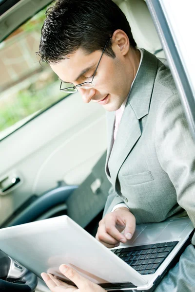Businessman working with laptop in the car — Stock Photo, Image