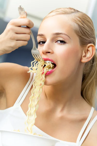 Gelukkig lachende jonge vrouw eten spaghetti binnenshuis — Stockfoto