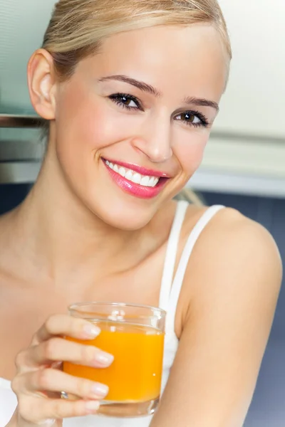 Portrait of young woman with orange juice, indoors — Stock Photo, Image