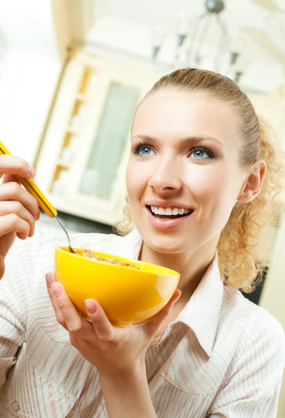 Молода усміхнена жінка їсть муслін вдома — стокове фото