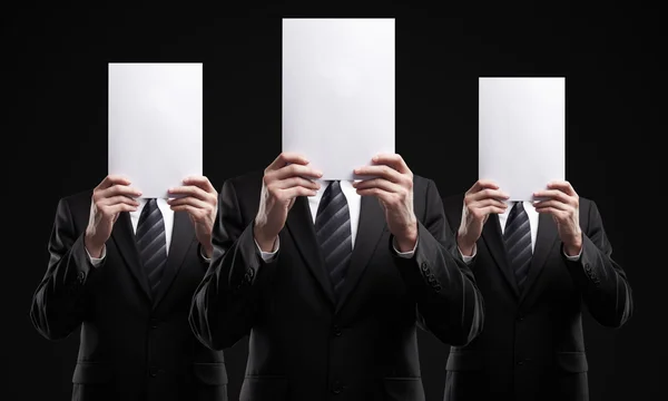 Group of business in dark suits holding a blank signs — Stock Photo, Image