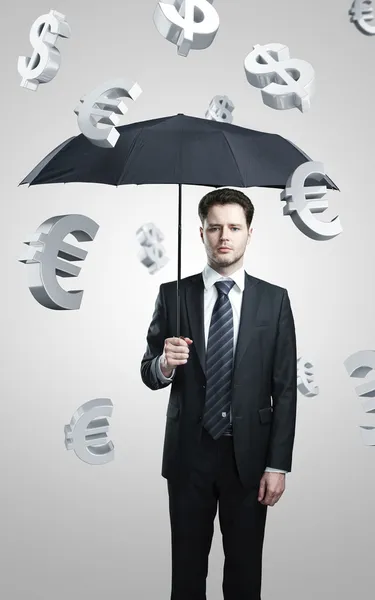 Деловой человек с зонтиком под знаком "Евро" и "Доллар" — стоковое фото