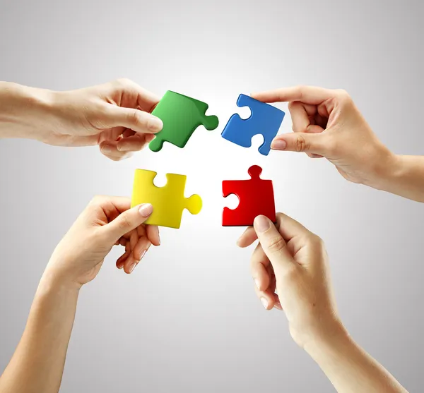 Hands and puzzle on gray background — Stock Photo, Image