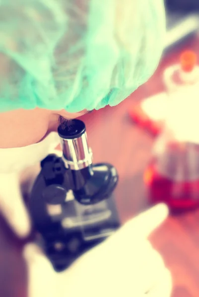 在化学实验室里用显微镜的女人 — 图库照片