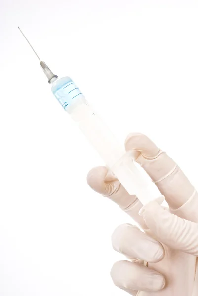 Mão segurando injeção no fundo branco com líquido azul — Fotografia de Stock