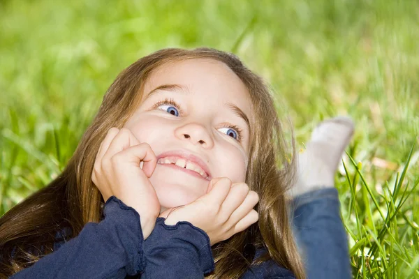 野の草で横になっている笑顔の女の子 — ストック写真