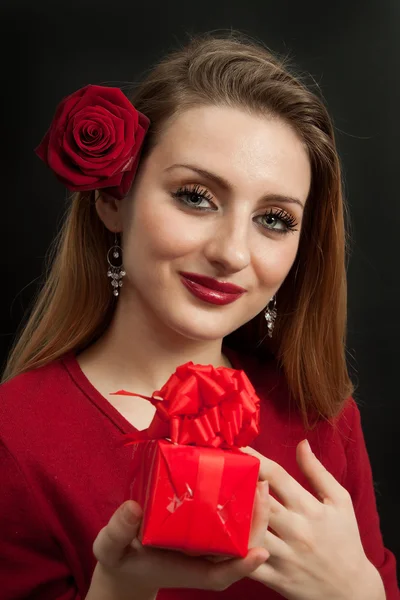 Gül desenli kırmızı hediye tutan güzel bir kız