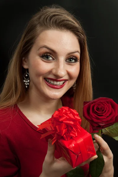 Beautiful girl with rose holding a red gift — Stock Photo, Image