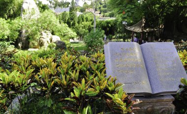 Book statue overlooking a garden in the park clipart