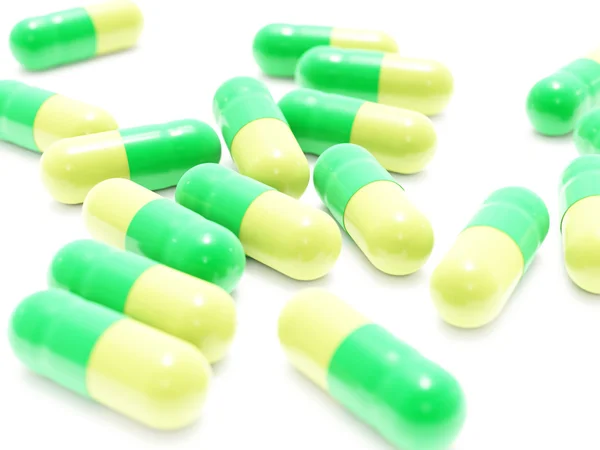Beaucoup de pilules vert-jaune sur blanc — Photo
