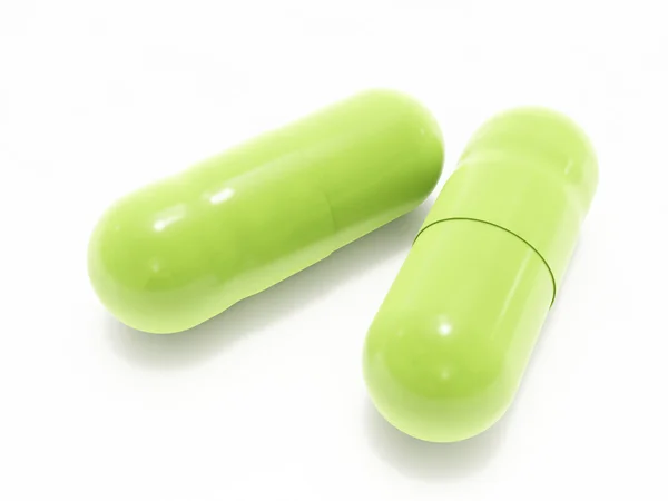 Две зеленые таблетки на белом — стоковое фото