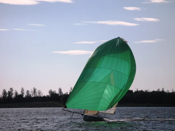 Green sailed Sailing Dinghy under a cloudy sky — Stock Photo, Image