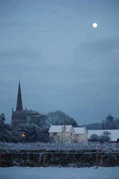 Måne över en vintrig byn scen — Stockfoto