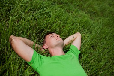 Young man lying on the grass clipart