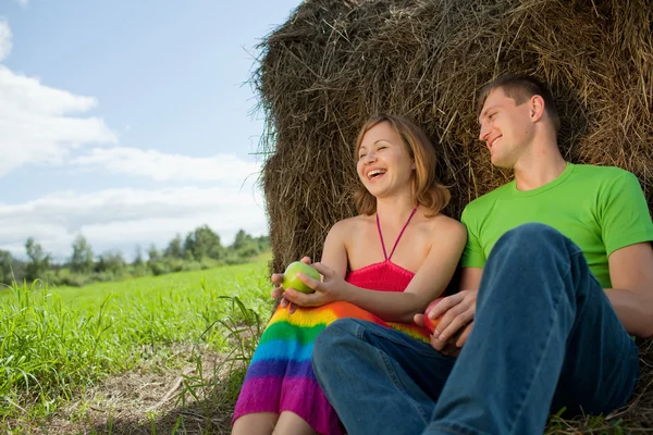 Couple with apples sitting on the grass hay — Stock Photo, Image