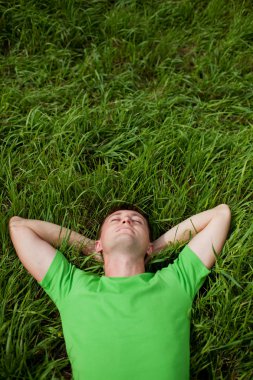 Young man lying on the grass clipart