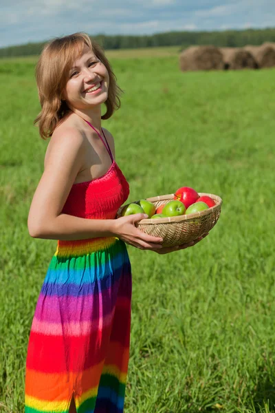 Leende flicka med en korg med äpplen — Stockfoto
