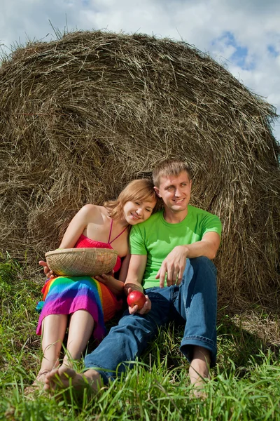 Couple with apples sitting on the grass hay — Stock Photo, Image