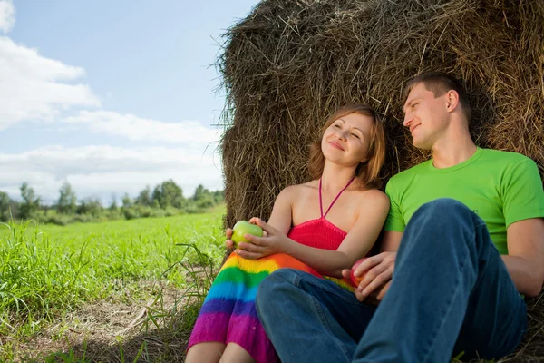Par med äpplen som sitter på gräs hö — Stockfoto