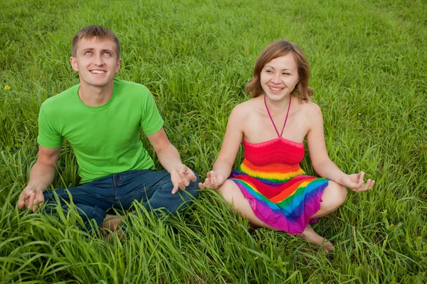 情侣在草地上和打坐在一起微笑 — 图库照片