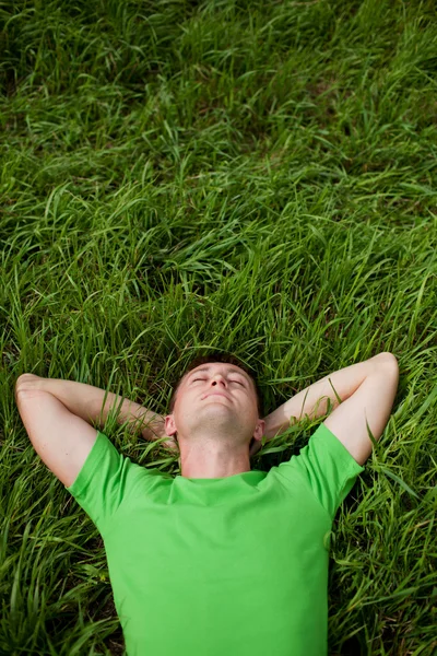 Jonge man liggend op het gras Rechtenvrije Stockfoto's