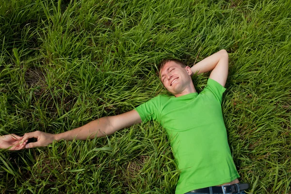 Junger Mann liegt im Gras und hält die Hand seiner Freundin lizenzfreie Stockfotos