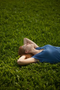 Girl lying on the grass and sleeping peacefully clipart