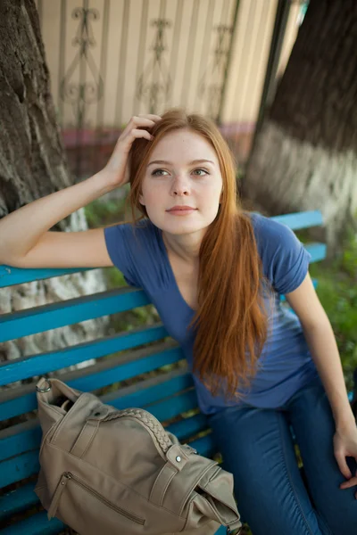 Triste fille assise sur un banc de parc — Photo