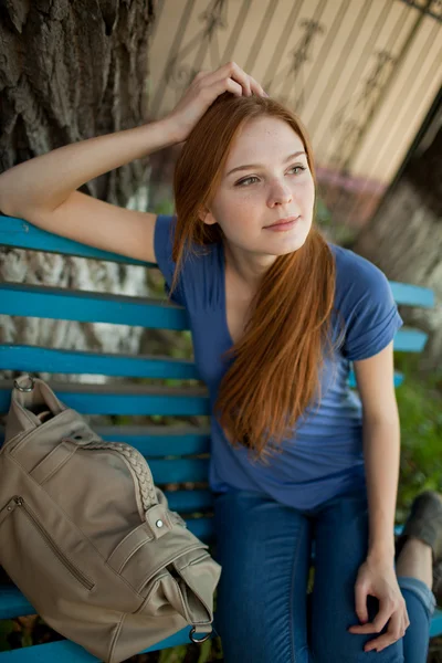 Triest meisje, zittend op een bankje — Stockfoto