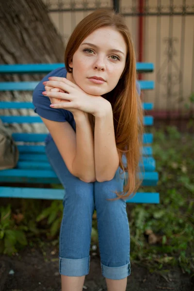 Грустная девушка сидит на скамейке в парке — стоковое фото