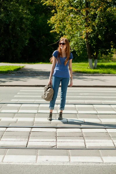 Chica con una bolsa va por el camino de la cebra peatonal — Foto de Stock