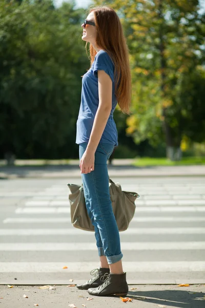 Chica con una bolsa va por el camino de la cebra peatonal — Foto de Stock