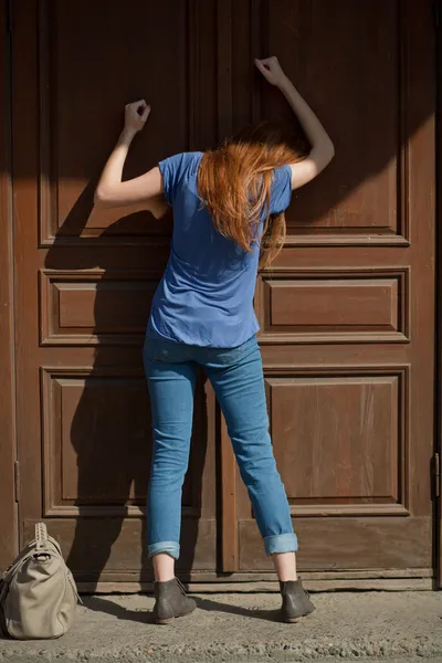 Отчаянная девушка стучит в закрытую дверь — стоковое фото