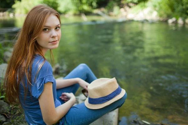Menina bonita sentada na margem do rio — Fotografia de Stock