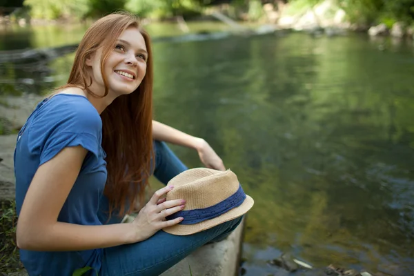 Hermosa chica sentada en la orilla del río —  Fotos de Stock