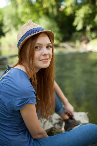 Beautiful girl sitting on the bank of the river — Stock Photo, Image