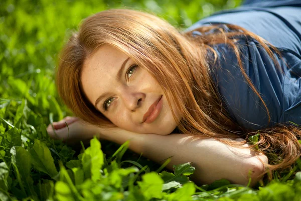 Tjej ligga på gräset och leende — Stockfoto