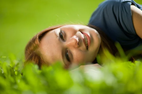 Menina deitada na grama e sorrindo — Fotografia de Stock