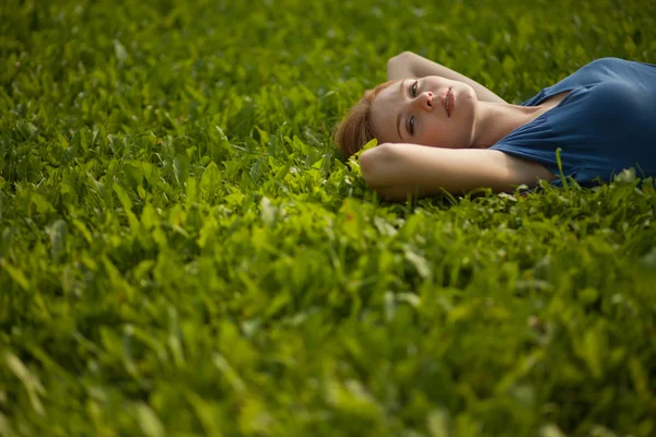 Meisje liggen op het gras en glimlachen — Stockfoto