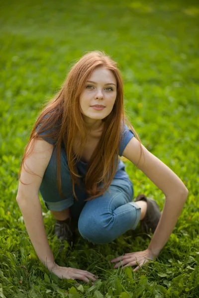 Beautiful red-haired girl sitting on grass — Stock Photo, Image