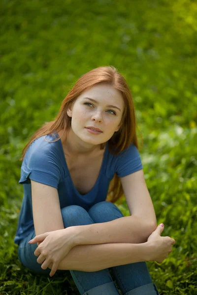 Krásná rusovlasá dívka sedící na trávě — Stock fotografie