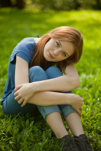 Красивая рыжая девушка сидит на траве — стоковое фото