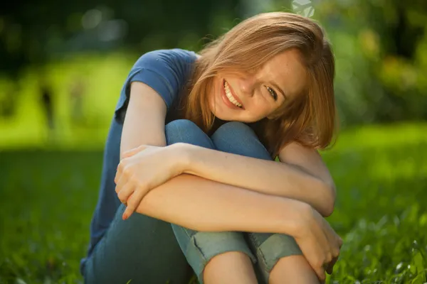 漂亮的红发女孩坐在草地上 — 图库照片